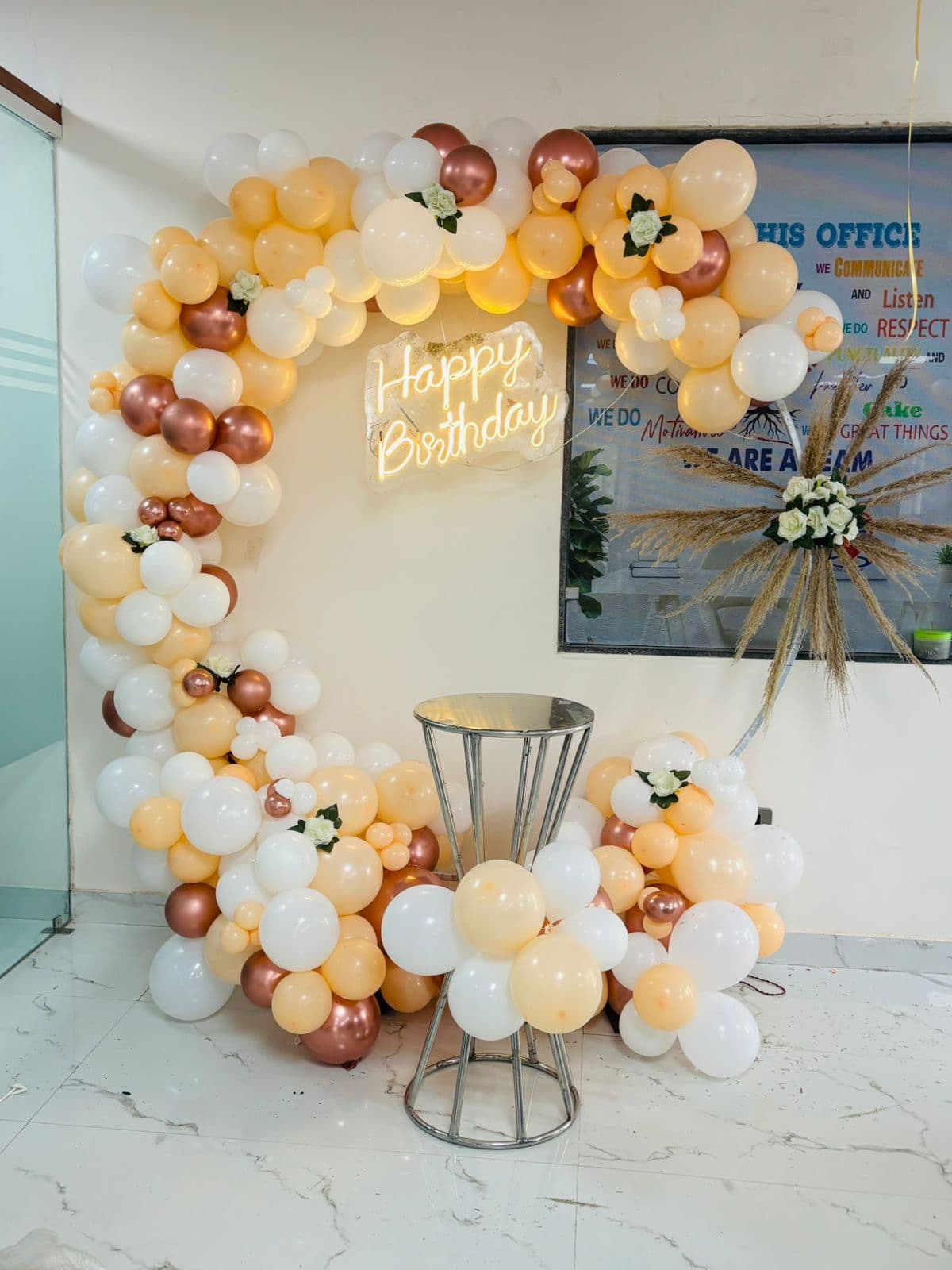 Cream, white and rose-gold balloon ring with a glowing neon 'Happy Birthday' sign
