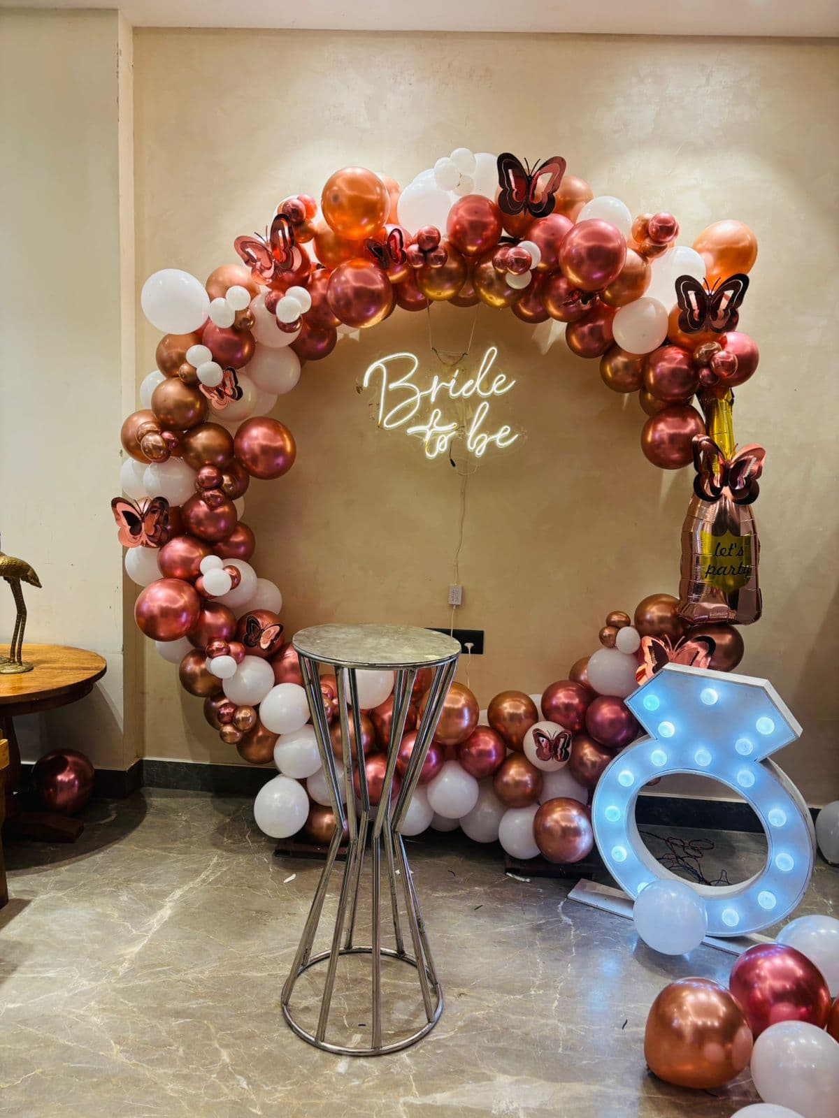 Rose-gold and white 'Bride to Be' balloon ring with butterflies and a lit ring marquee