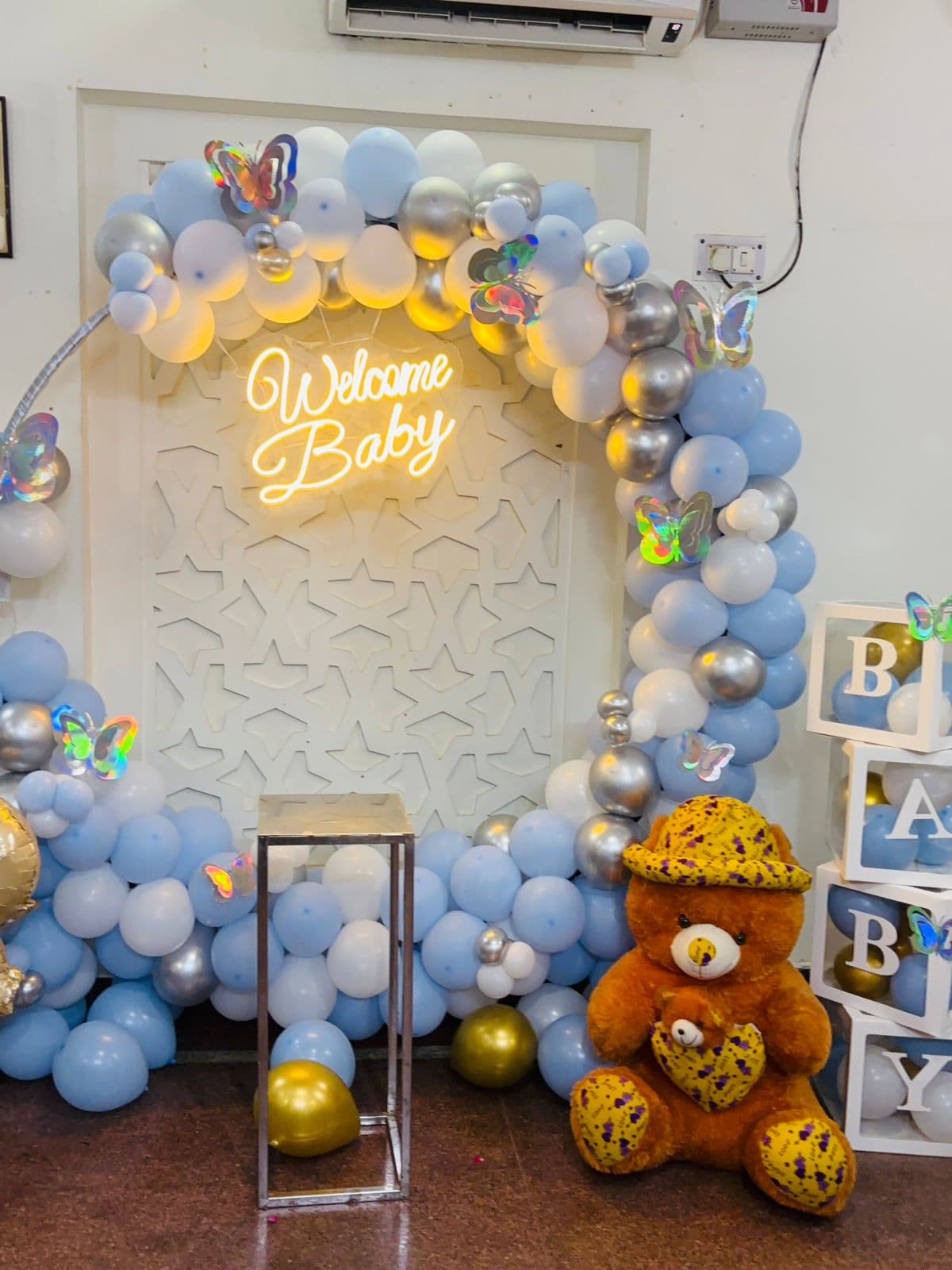 Blue, white and silver 'Welcome Baby' arch with butterflies and a teddy